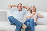 Happy relaxed couple sitting on sofa in living room