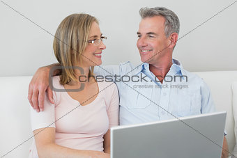 Relaxed couple using laptop at home
