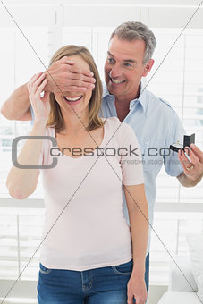 Smiling man surprising woman with a wedding ring