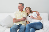 Relaxed couple with wine glasses sitting on sofa