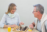 Couple playing chess while having orange juice