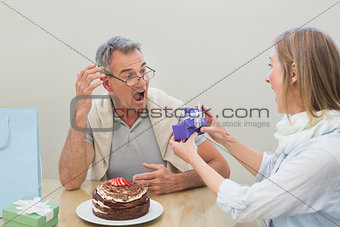 Shocked man receiving a gift by cake on table