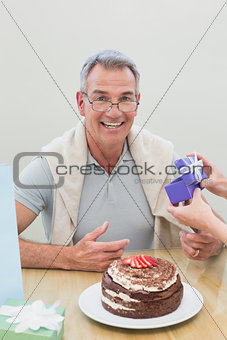 Portrait of a man receiving a gift by cake