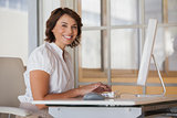Smiling businesswoman using computer at office desk
