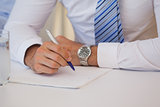 Mid section of a businessman writing document