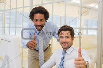 Smiling businessmen gesturing thumbs up in office