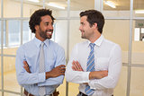 Two smiling businessmen with arms crossed in office