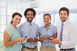 Smiling business colleagues text messaging in office