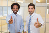 Smiling businessmen gesturing thumbs up in office