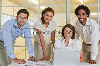 Happy business people using laptop in meeting at office