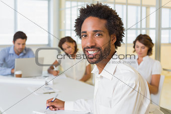 Smiling businessman with colleagues in meeting at office
