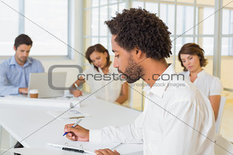 Businessman writing document with colleagues in meeting