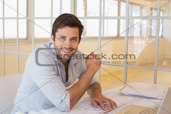 Smiling businessman working on blueprints in office
