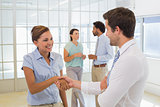 Business people shaking hands with colleagues in office