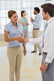 Business people shaking hands with colleagues at office
