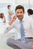 Smiling businessman on call with colleagues at office