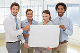 Happy business colleagues holding blank placard in office