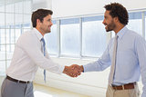 Smiling young businessmen shaking hands in office