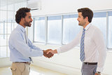 Smiling young businessmen shaking hands in office