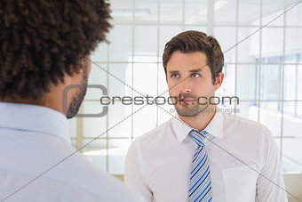 Serious businessmen looking at each other in office