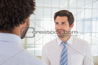 Smiling businessmen looking at each other in office