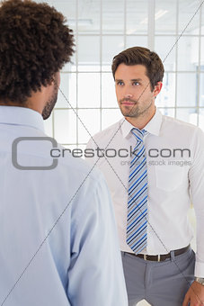 Serious businessmen looking at each other in office