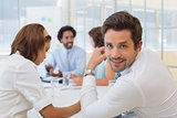 Smiling young businessman with colleagues in meeting