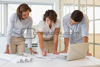 Business people working on blueprints at office