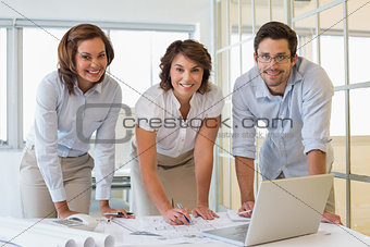 Confident business people working on blueprints at office