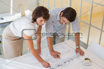 Business people working on blueprints at office