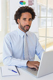 Portrait of businessman using laptop at office desk