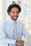 Smiling businessman using laptop at office desk