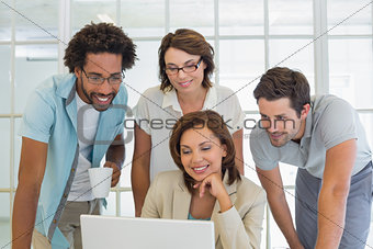 Smiling business people using laptop together