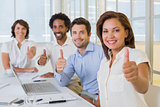 Business people gesturing thumbs up in meeting at office