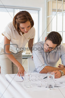 Concentrated colleagues working on blueprints at office