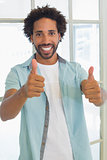 Smiling casual businessman gesturing thumbs up in office