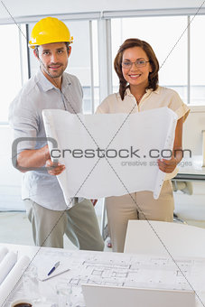Two business people working on blueprints in office