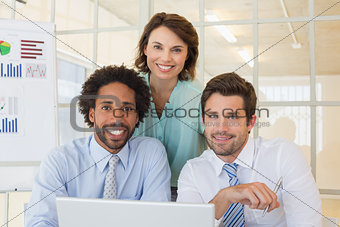 Smiling business people using laptop at office