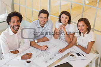 Smiling colleagues working on blueprints in office