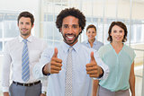 Businessman with colleagues gesturing thumbs up in office