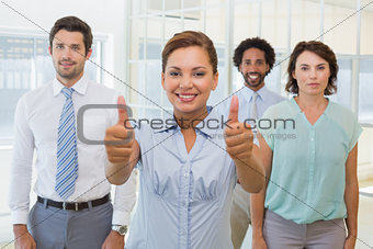 Businesswoman with colleagues gesturing thumbs up
