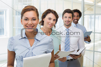 Business colleagues holding notepads in row at office
