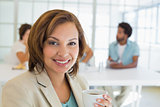 Smiling businesswoman having coffee with colleagues in meeting