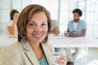 Smiling businesswoman having coffee with colleagues in meeting