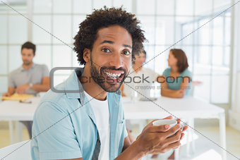 Cheerful businessman having coffee with colleagues at office
