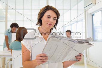 Businesswoman reading newspaper with colleagues in meeting