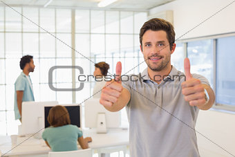 Businessman gesturing thumbs up with colleagues in meeting