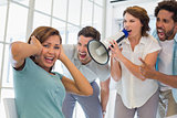 Colleagues yelling through megaphone at businesswoman