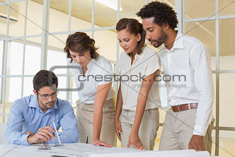 Business colleagues working on blueprints at office