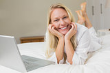 Woman with laptop on bed at home